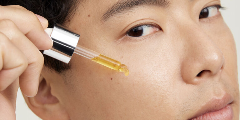 Male model applying serum to cheek