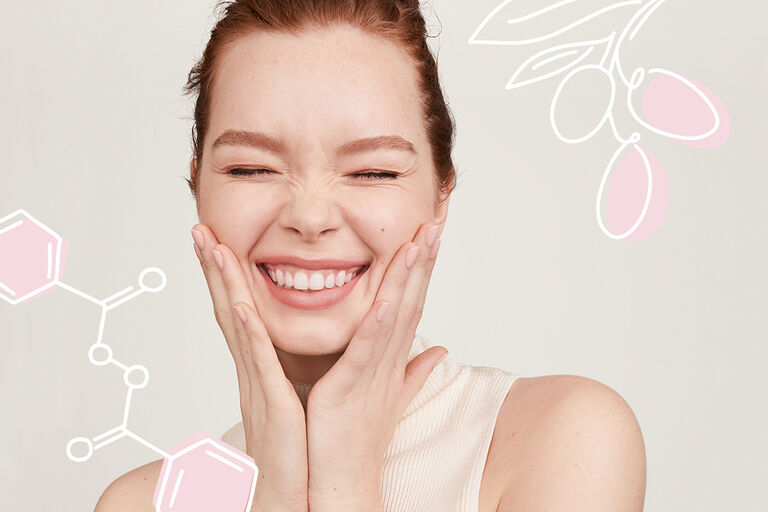 Woman smiling with her hands by her cheeks. In the background are illustrations of Mary Kay active ingredients