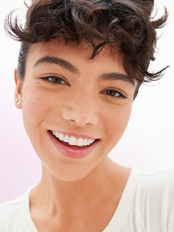 A female model wearing natural makeup looks into the camera.